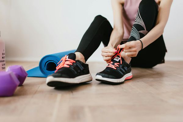 Close up of sneakers and exercise mat on a wooden floor